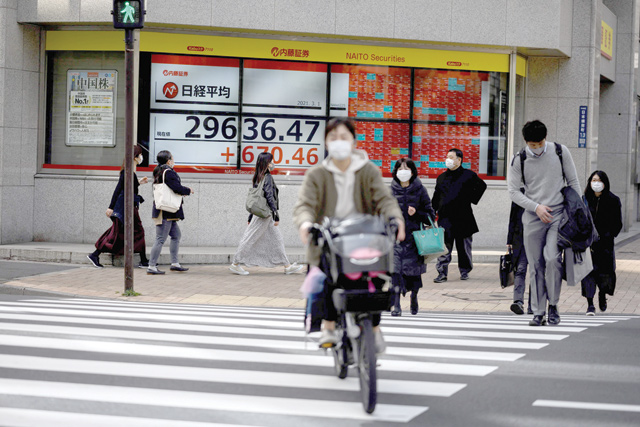 Pedestrians walk in front of an electronic quotation board displaying the numbers of share prices on the Tokyo Stock Exchange in Tokyo on Monday (AFP photo)