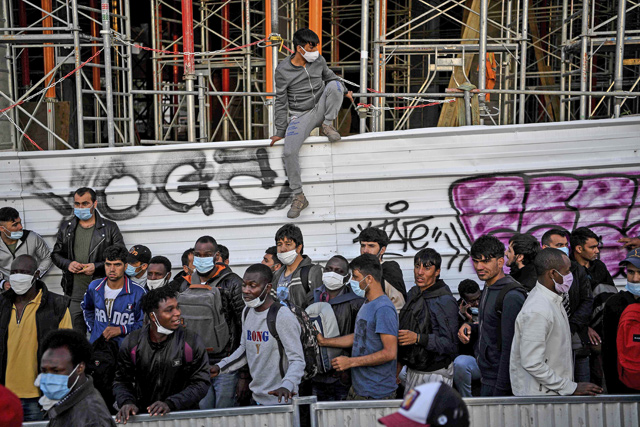 Asylum seekers queue during their evacuation from a makeshift camp set along the Canal Saint-Denis in Aubervilliers near Paris early on Wednesday  (AFP photo)