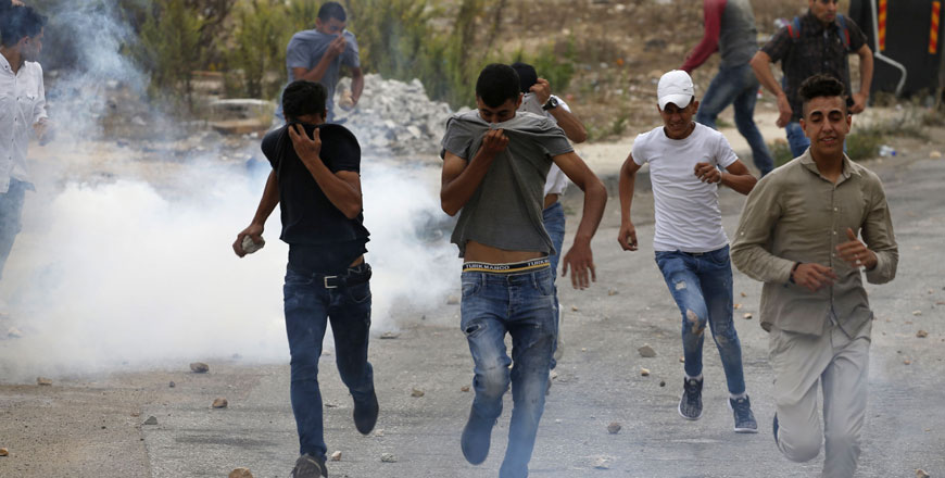 Palestinian youths run away from tear gas fired by Israeli occupation forces during confrontations in the city of Ramallah after the forces broke into a number of buildings in West Bank on Sunday (AFP photo)