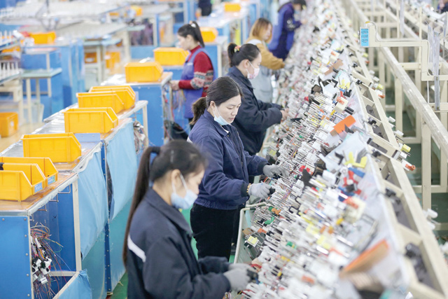 This photo shows employees working on a wire harness production line at a factory in Huaibei, eastern China's Anhui province on Tuesday as the has hiked its 2021 global growth forecast (AFP photo)