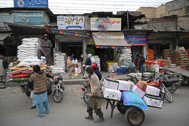Labourers pull carts loaded with grain sacks at a grocery market in Rawalpindi,  on Monday  (AFP photo)