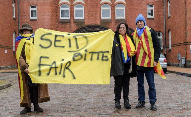 Protesters wearing Catalan pro-independence Estelada flags hold a banner reading ‘Please be fair’ in front of the prison in Neumuenster, northern Germany, where former Catalan regional president Carles Puigdemont is detained, on Tuesday (AFP photo)