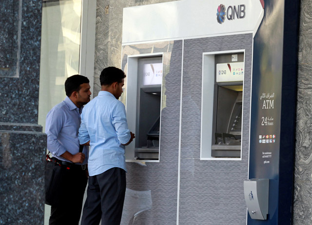Men withdraw cash from an ATM outside Qatar National Bank (QNB) in Doha, Qatar, on Sunday (Reuters photo)