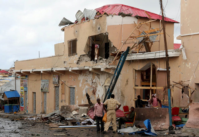 People stand near debris at the scene of an explosion at the gate of Siyad Hotel after Friday night's attack in Somalia's capital Mogadishu on Saturday (Reuters photo)