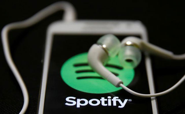 Earphones are seen on top of a smart phone with a Spotify logo on it in this February 20, 2014 photo (Reuters file photo )