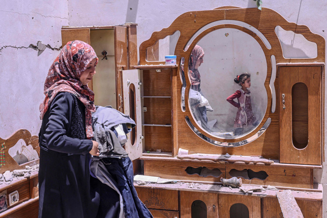 A Palestinian woman searches for the families belongings at their house, after it was destroyed by an Israeli air strike in the city of Rafah, in the southern Gaza Strip, on Sunday (AFP photo)