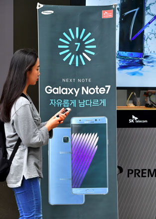This file photo taken on September 12, 2016, shows a woman walking past billboards advertising the Samsung Galaxy Note 7 at a mobile phone shop in Seoul. The world's biggest smartphone maker Samsung blamed faulty batteries on Monday for the fires that led to the recall of its flagship Galaxy Note 7 device (AFP photo)