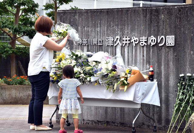 This photo taken on July 28, 2016 shows a mother and her daughter offering flowers for the victims after a man went on a knife rampage, at the main entrance to the Tsukui Yamayuri En care centre in Sagamihara, Kanagawa prefecture (AFP file photo)