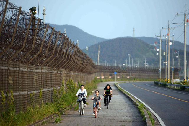 In this photo taken on May 24, 2018, a family ride bicycles along a barbed wire fence of the De-militarised Zone separating North and South Korea, on Ganghwa island, on the border with North Korea (AFP file photo)