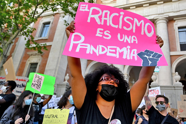 A protester holds a placard reading ‘Racism is a pandemic’ in Madrid, on Sunday, during a demonstration against racism and in solidarity with the Black Lives Matter movement, in the wake of the killing of George Floyd, an unarmed black man who died after a police officer knelt on his neck in Minneapolis (AFP photo)