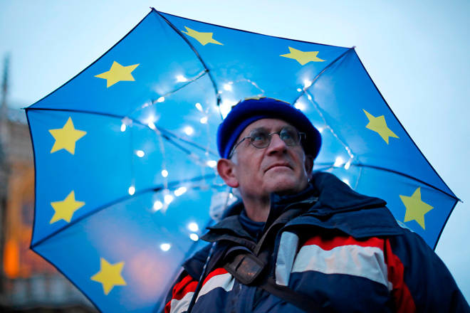 A pro-EU protester shelters from the rain under a European flag umbrella as he demonstrates outside the Houses of Parliament in central London on Tuesday (AFP photo)