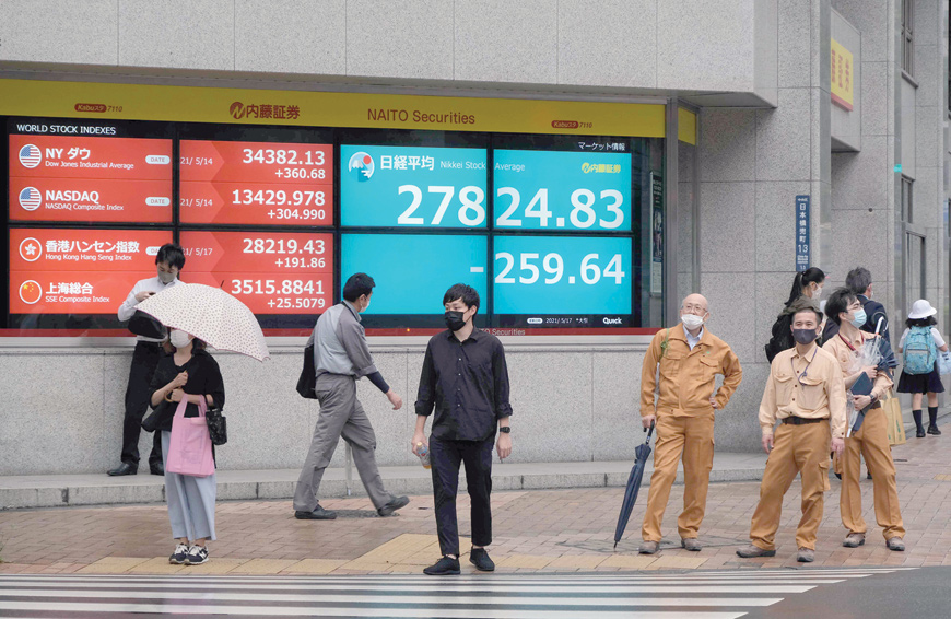 People stand in front of an electronic quotation board displaying the closing numbers of share price at the Tokyo Stock Exchange in Tokyo, on Monday (AFP photo)