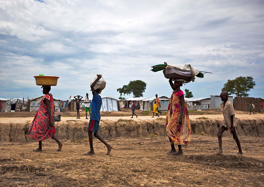 This file photo taken on September 17 shows a woman, her cousin, her son and her son’s friend carrying their belongings as they walk through the United Nations base outside Bentiu, which hosted around 118,000 people uprooted during the country’s civil war (AFP photo)
