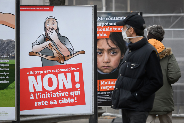 A man looks at a campaign banner reading in French ‘Responsible enterprise, NO to the initiative that misses its target’ displayed in the streets of Geneva, on Sunday (AFP photo)