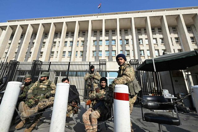 Anti government forces stand guard in front of Syria’s Central Bank in Damascus, on Monday  (AFP file photo)