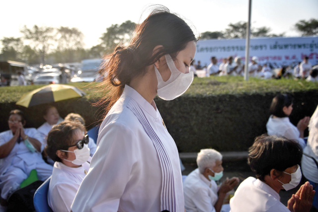 Devotees wearing protective face masks attend outdoor mass prayer at Wat Dhammakaya Buddhist temple in Bangkok, on January 31 (AFP photo)