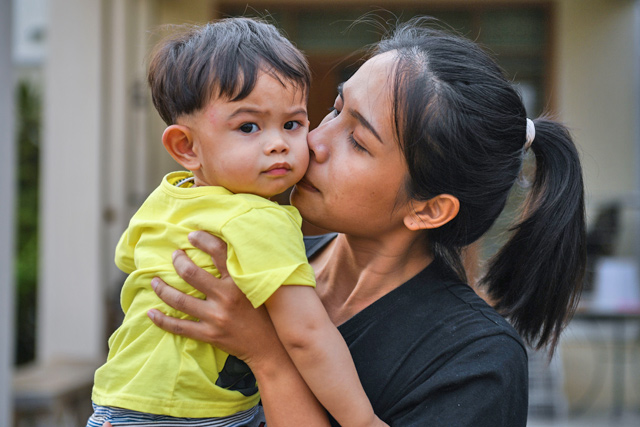 Partiya Aree, 29, a survivor of a mass shooting at a northeastern Thai shopping mall, hugs her one-year-old son as she describes her ordeal during an interview with AFP in Nakhon Ratchasima on Monday (AFP photo)