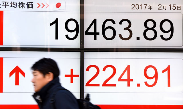 A man walks past an electric quotation board flashing the Nikkei key index of the Tokyo Stock Exchange in front of a securities company in Tokyo on Wednesday (AFP photo)