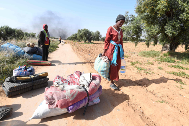 Migrants leave with their belongings from a camp for undocumented migrants from sub-Saharan Africa at al-Amra on the outskirts of the Tunisian port city of Sfax today after authorities started dismantling the camp (AFP photo)