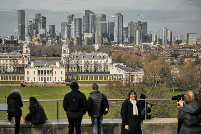 People look at the view with Old Royal Naval College back dropped by the Canary Wharf financial district, from Greenwich Park, southeast London, on Friday (AFP photo)