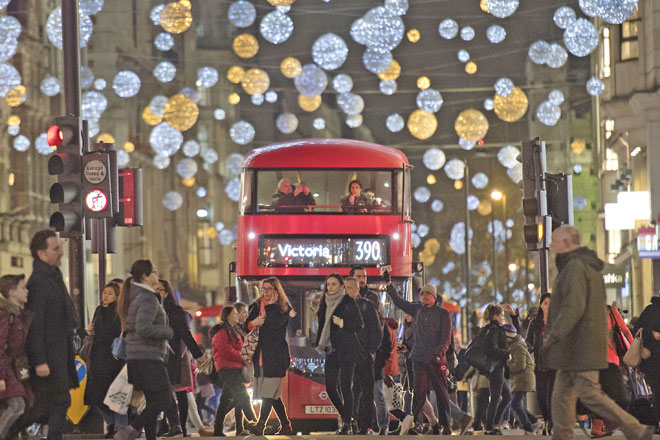 This photo taken on Friday shows shoppers crossing in front of a London bus as it travels under Christmas lights on Oxford Street in central London (AFP file photo)