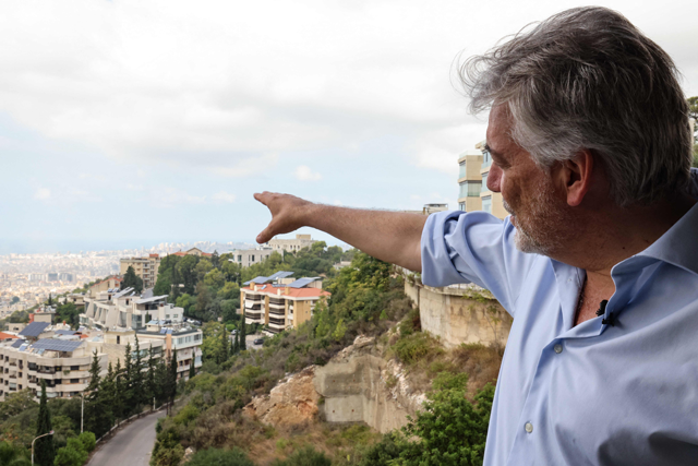 United Nations Interim Force in Lebanon (UNIFIL) spokesperson Andrea Tenenti points at Beirut's southern suburbs from his office at the UNIFIL House in Baabda east of the Lebanese capital on Saturday (AFP photo)
