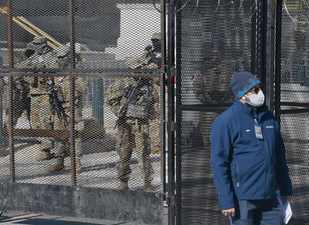 A man walks past members of the National Guard positioned at a security checkpoint near the US Capitol, ahead of the 59th inaugural ceremony for President-elect Joe Biden and Vice President-elect Kamala Harris in Washington, DC, on Tuesday (AFP photo)