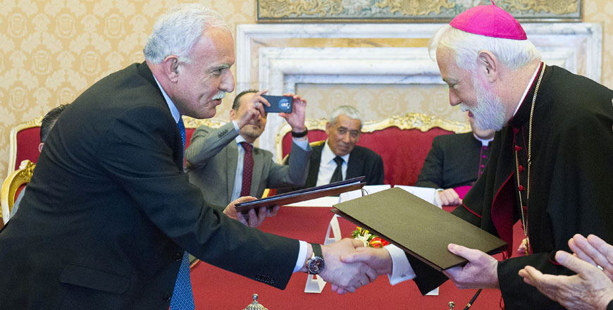 Vatican’s State Relations Secretary Paul Richard Gallagher (right) shakes hands with Palestinian Foreign Minister Riad Al Malki after signing a Vatican-Palestine territories accord at the Vatican on Friday (AFP photo/Osservatore Romano)
