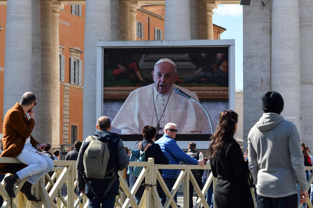 People watch a screen live-broadcasting Pope Francis' Sunday Angelus prayer on St Peter's Square at the Vatican on Sunday (AFP photo)