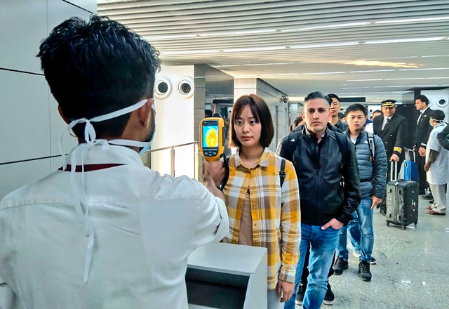 In this photo taken on Tuesday, a man (left) uses a thermographic camera to screen the head of people at Netaji Subhash Chandra Bose International Airport in Kolkata, following the ministry of health and family welfare’s advisory to screen passengers arriving in India from China and Hong Kong regarding the novel coronavirus issue (AFP photo)