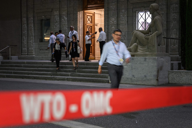 Delegation members are seen at the entrance of the WTO headquarters during the 12th WTO Ministerial Conference in Geneva early on Friday (AFP photo)
