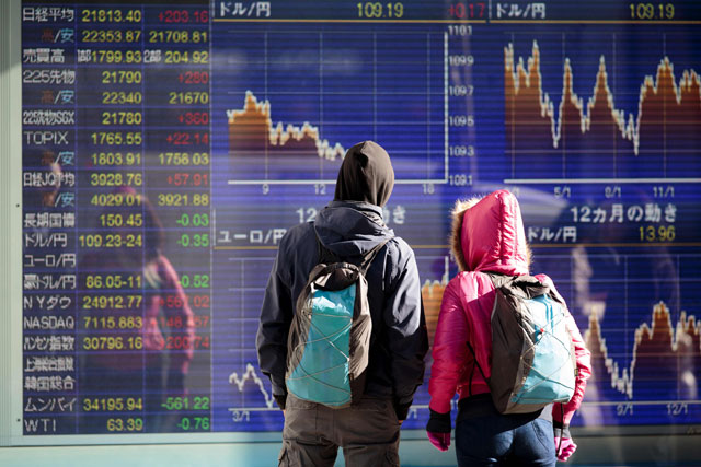 Tourists look at a stock indicator showing the foreign exchange rate of the Japanese yen against the US dollar and euro in Tokyo on Wednesday (AFP photo)