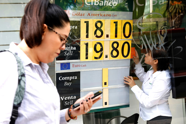 An employee changes the board with the exchange rate for Mexican peso and US dollar at a CI Bank branch in Mexico City, Mexico, on Friday  (Reuters photo)