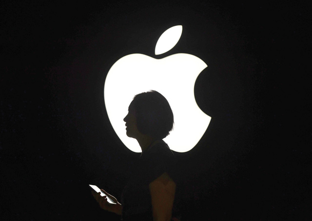 A reporter walks by an Apple logo during a media event in San Francisco, California, on September 9, 2015 (AFP file photo)