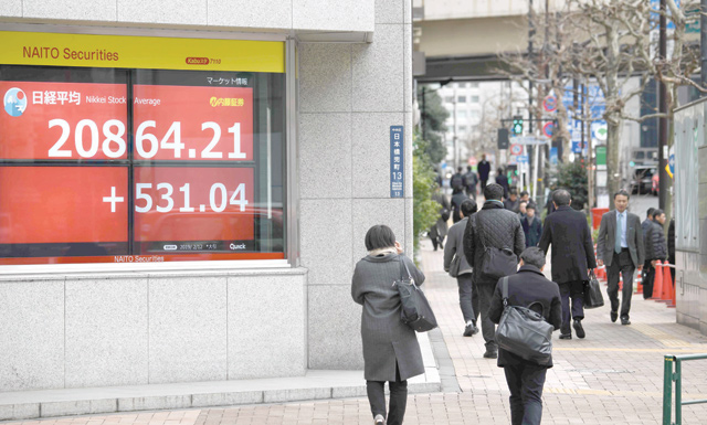 Pedestrians walk past the closing rate of the Tokyo Stock Exchange displayed in the window of a security company in Tokyo on Tuesday (AFP photo)