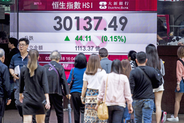 Pedestrians walk past an electronic sign displaying the closing stock numbers for the Hang Seng Index in Hong Kong on Tuesday as Asian stocks finished on the back foot, following Wall Street lower as fears of a trade war between the US and China hit market sentiment (AFP photo)