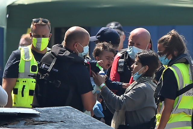 A mother is reunited with her child as migrants, believed to have been picked up from boats in the Channel, are processed by Border Patrol officers in the port of Dover, on the south-east coast of England, on Sunday  (AFP photo)