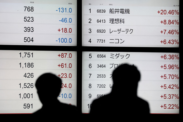 Pedestrians walk past an electronic quotation board displaying Japanese companies' stock prices on the Tokyo Stock Exchange in Tokyo on Wednesday (AFP photo)