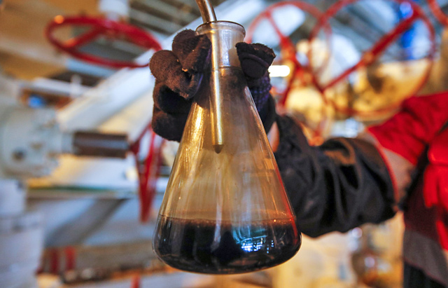 An employee takes a sample of oil at the Filanovskogo platform operated by Lukoil company in Caspian Sea, Russia, on October 16, 2018 (Reuters file photo)