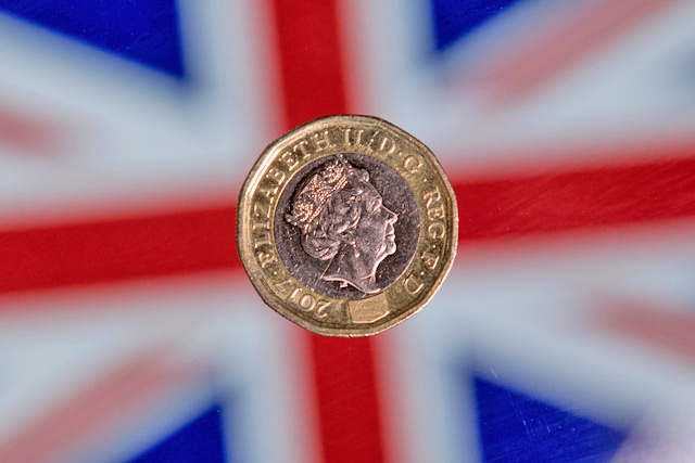 In this photo taken on December 14, 2017, a British one pound sterling coin is arranged for a photograph in front of a union flag in London  (AFP file photo)