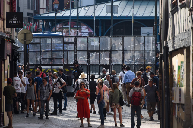 People walk in the street in front of a mesh movable barrier installed by French gendarmes in Bayonne, southwest France, on Saturday, ahead of expected protests on the sidelines of the annual G-7 Summit attended by the leaders of the world's seven richest democracies, Britain, Canada, France, Germany, Italy, Japan and the United States (AFP photo)