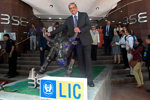 Mangalam Ramasubramanian Kumar (centre), chairman of the Life Insurance Corporation of India poses with the bronze statue of a bull at the Bombay Stock Exchange in Mumbai, on Tuesday (AFP photo)