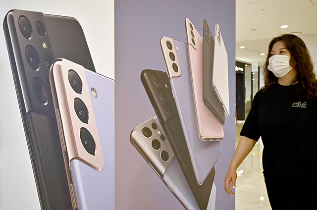 In this photo taken on July 7, 2021, a woman walks past an advertisement for the Samsung Galaxy S21 smartphone at the company's showroom in Seoul.  (AFP photo)