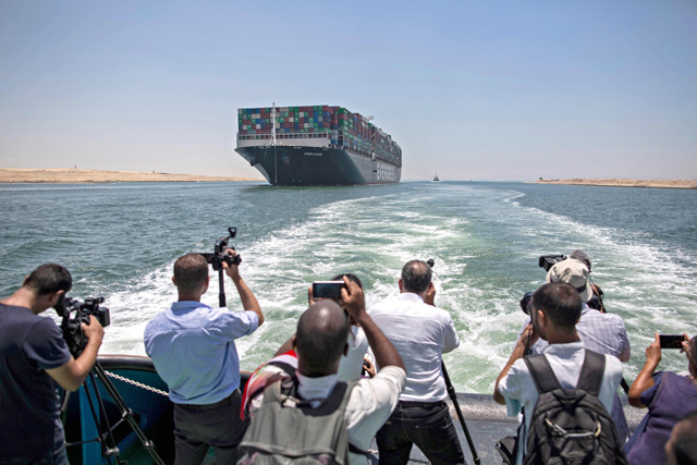 Journalists on a nearby boat film the Panama-flagged MV 'Ever Given' container ship sailing along Egypt's Suez Canal near the canal's central city of Ismailia, on Monday (AFP photo)