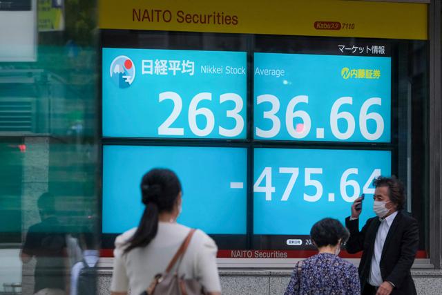 Pedestrians walk past an electronic share price board showing the closing numbers on the Tokyo Stock Exchange in Tokyo, on Tuesday  (AFP photo)