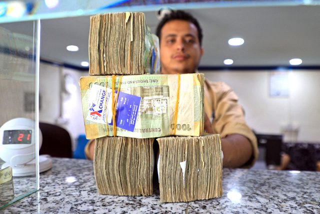 An employee displays stacks of Yemeni riyal banknotes at a currency exchange office in Yemen's capital Sanaa, on August 16 (AFP photo)