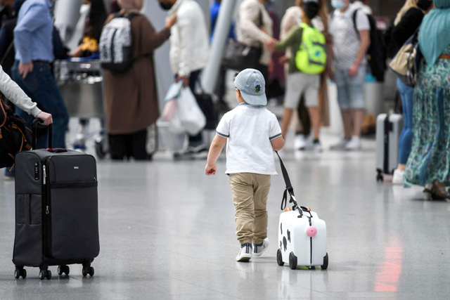 A little boy walks with his suitcase past travellers queing at the check-in counter on Friday at the airport of Duesseldorf as summer holidays begin in this western German area (AFP photo)