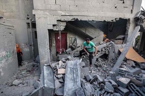 A woman looks on as a man inspects the damage on the rubble of a building hit in an Israeli strike in the Bureij camp for Palestinian refugees in the central Gaza Strip on May 2, 2025