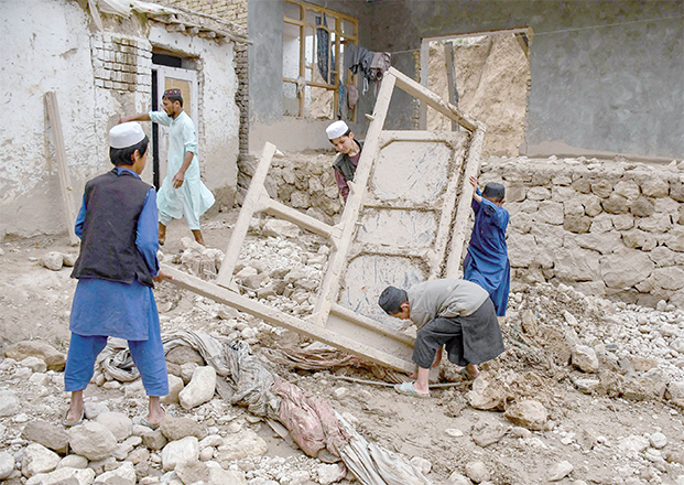 Afghan children remove a window frame inside the debris of a damaged house following flash floods at the Baklak village in Dahaneh-ye Ghowri district of Baghlan province on Sunday (AFP photo)