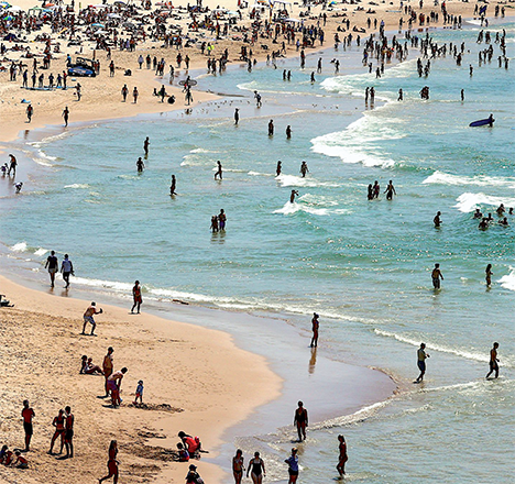 Beachgoers carry surfboards and swim on a hot summer day at Sydney’s Bondi Beach on Saturday (AFP photo)